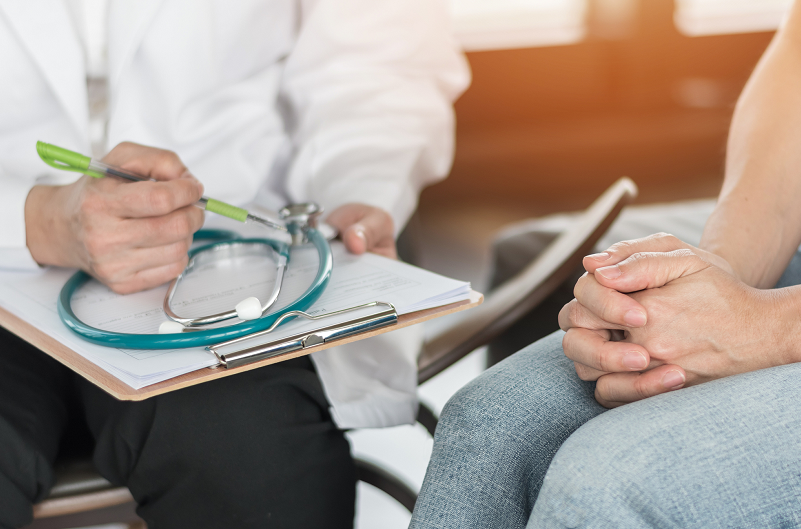 Woman has her hands in her lap, nervous, during a doctor's visit.