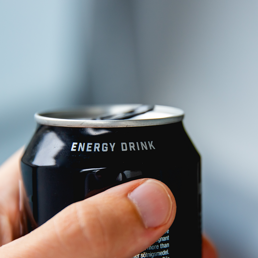 Close-up of a hand holding a can of energy drink.