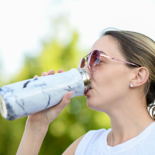 A woman takes a drink from her water bottle during a workout.