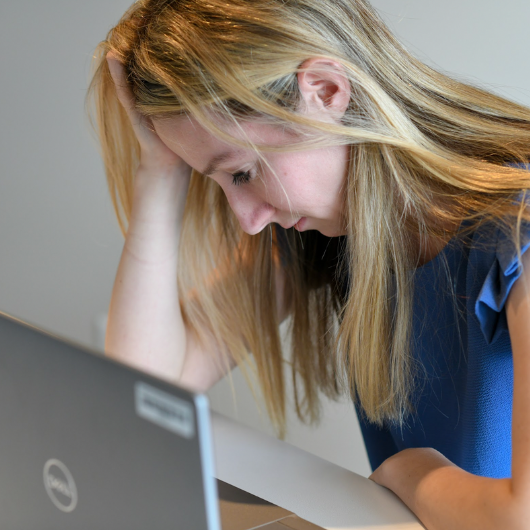 A young woman with a painful migraine holds her hand to her forehead.