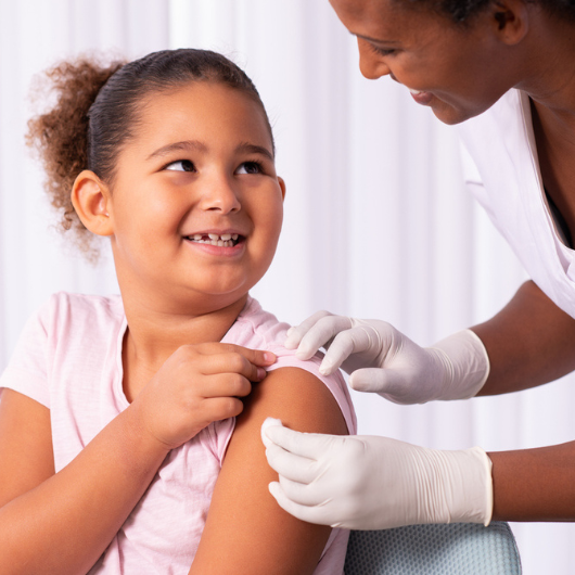 An adolescent girl gets a bandage on her upper arm after a vaccine.