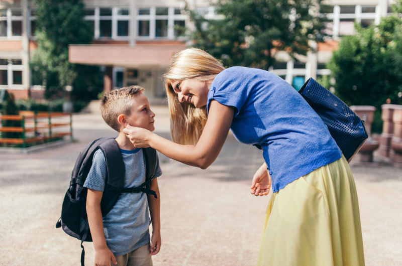 A mom reaches out to comfort her young son, who is going back to school.