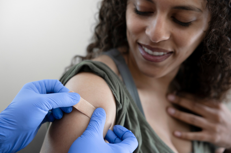 Woman getting a band aid applied after receiving a COVID shot.