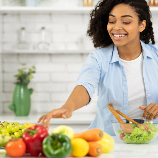 A Black woman prepares a healthy lunch for her family in a modern kitchen.