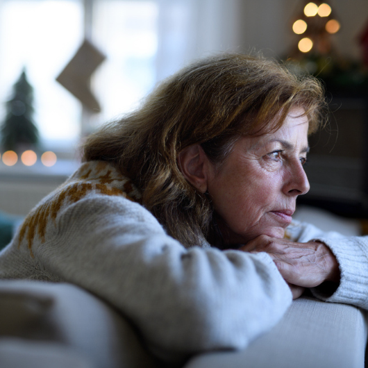 Portrait of lonely senior woman sitting on sofa indoors during the holidays.