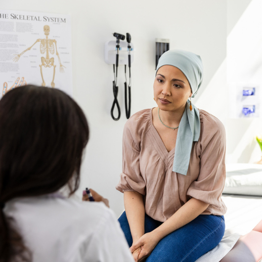 An adult female cancer patient listens as a doctor talks to her about potential clinical trials.