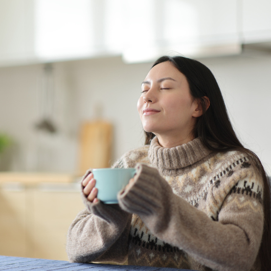Asian woman relaxing and drinking coffee in the kitchen in winter.