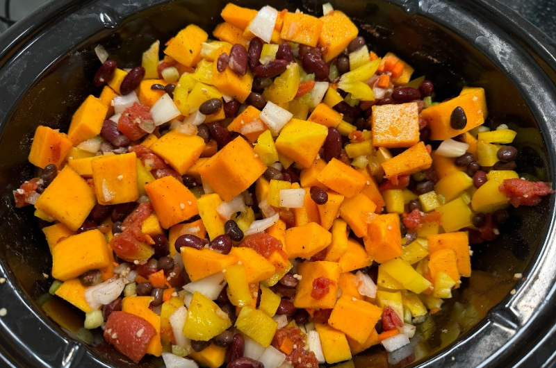 A top-down view of a slow cooker holding butternut squash chili.