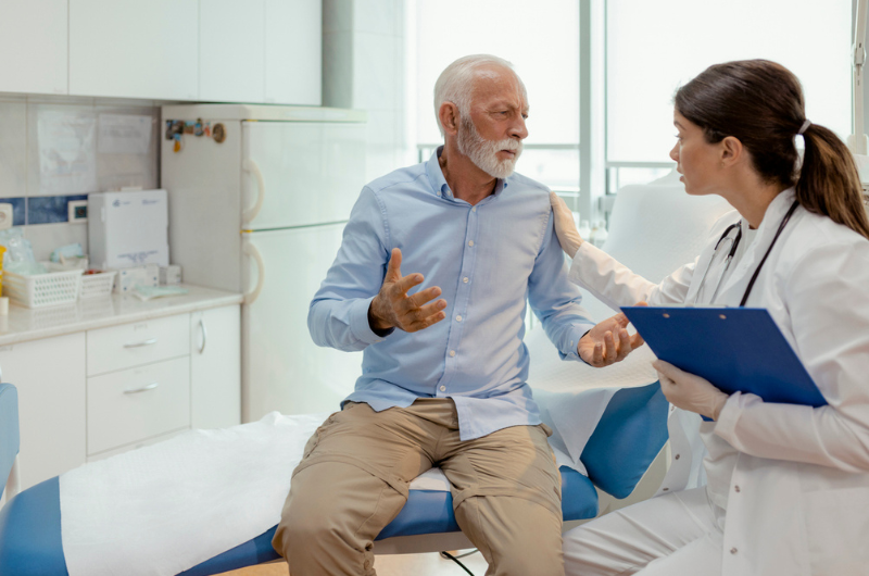 Unhappy senior patient discussing his diagnosis with a female doctor at a hospital.