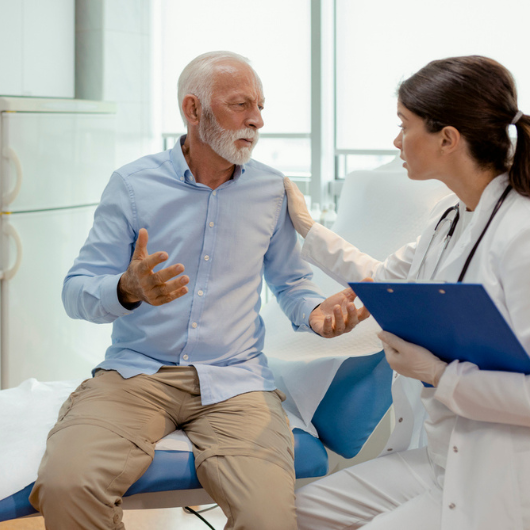 Unhappy senior patient discussing his diagnosis with a female doctor at a hospital.