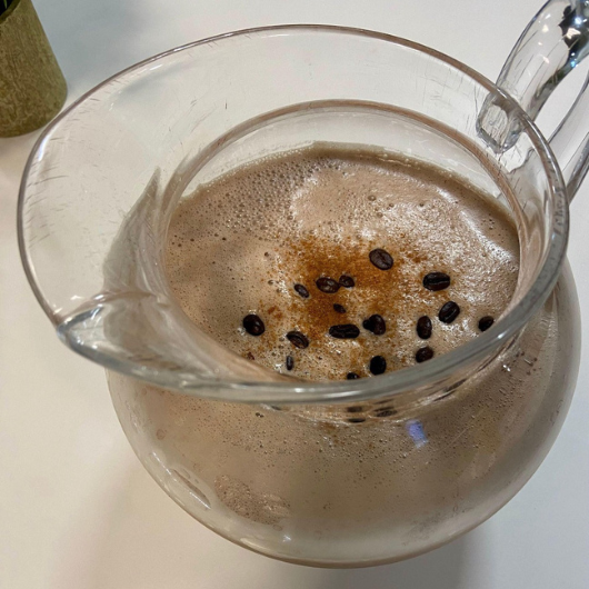 Top-down view of a Tahini coffee smoothie in a large glass pitcher.
