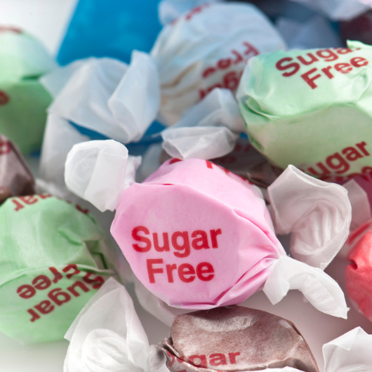 Sugar-free candies coming out of the bag on white background.