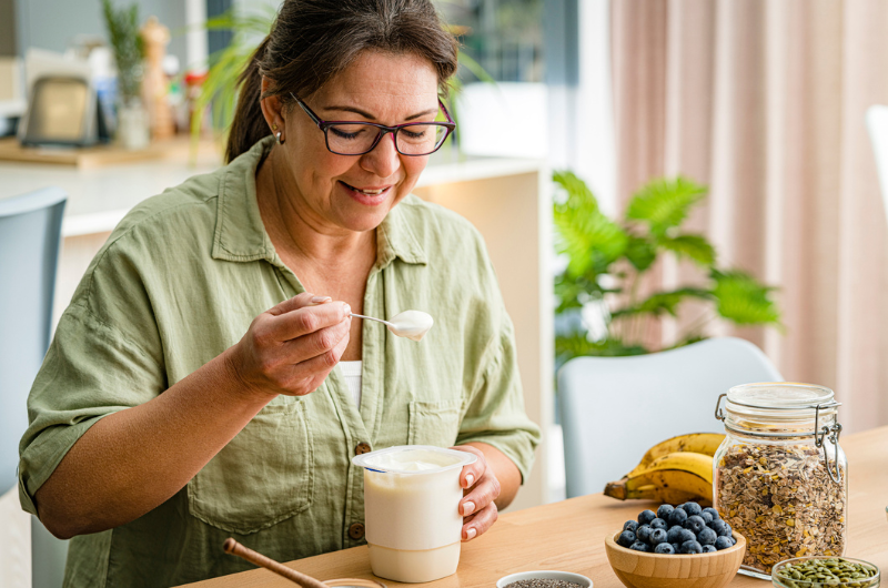 Middle-aged woman eating Greek yogurt.