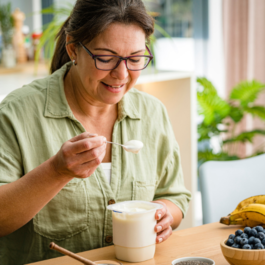 Middle-aged woman eating Greek yogurt.