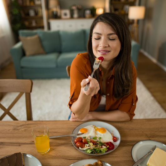  Happy woman eats breakfast at home and enjoys the taste.