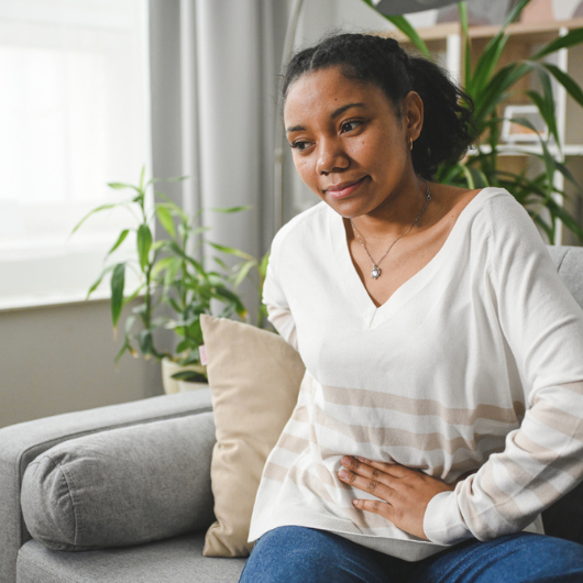 Young adult woman clutches her stomach.