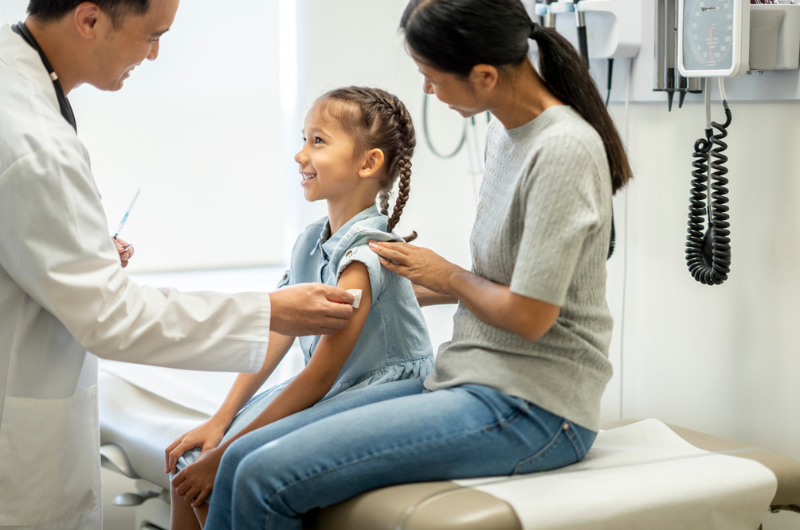 A doctor disinfects a young girl's arm in preparation for a medical injection.