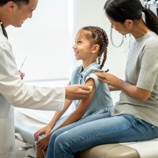 A doctor disinfects a young girl's arm in preparation for a medical injection.