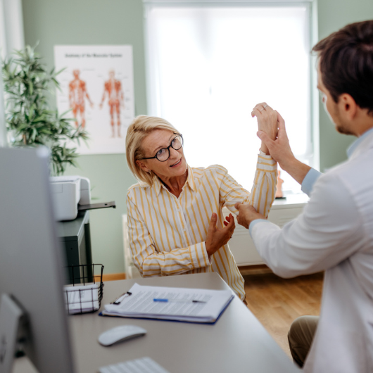 Mature woman having her arm checked by doctor at doctor's office