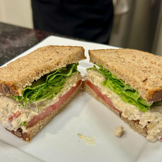 A chickpea “tuna” salad sandwich on wheat bread, sliced in half.
