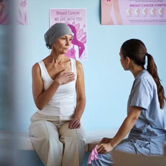 Middle-aged Caucasian woman wearing headscarf sits on an examination table.