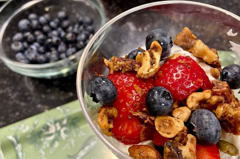 A top-down view of a glass of omega-3 grain-free granola with strawberries and blueberries.  