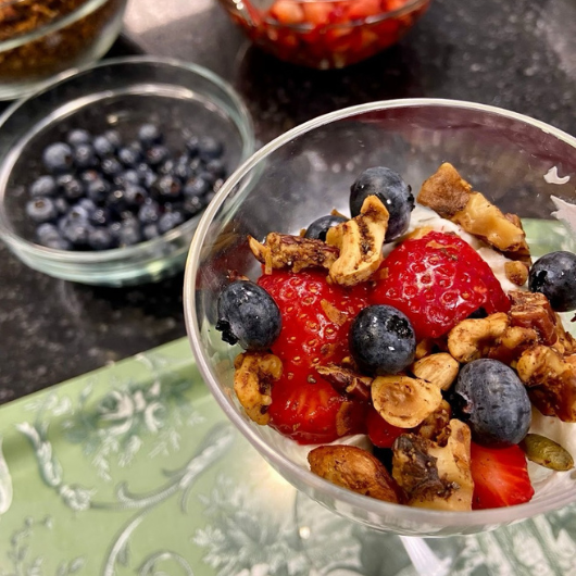 A top-down view of a glass of omega-3 grain-free granola with strawberries and blueberries.  