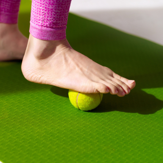 a foot using tennis ball to roll out pain