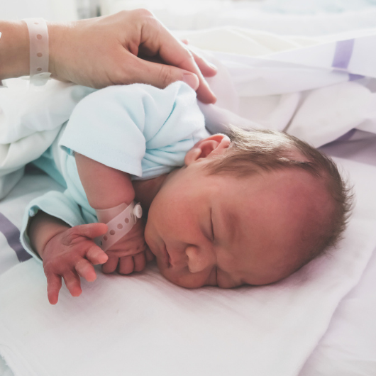 Mother and newborn resting after childbirth in maternity hospital room.