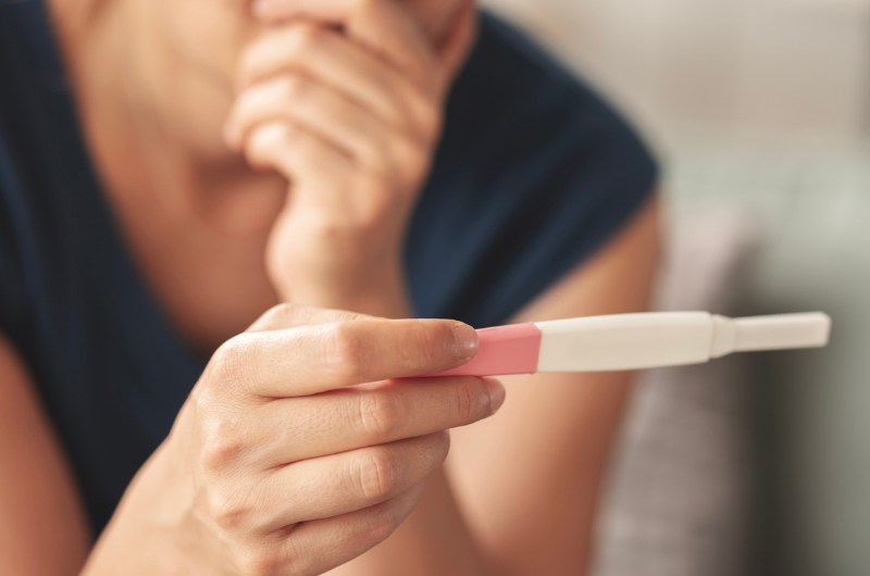 Young woman holding pregnancy test with negative result