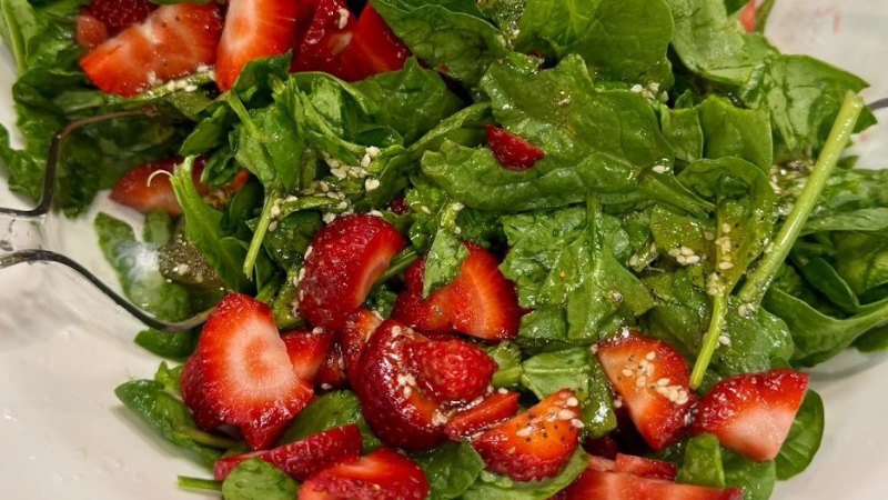 A healthy salad featuring ripe strawberries and fresh spinach.
