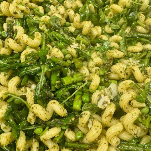Top-down view of spring pasta salad made with vegetables, pasta and fresh herbs. 