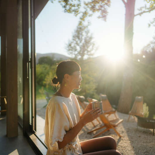 A woman sipping a warm cup of tea in the morning, basking in the sun.