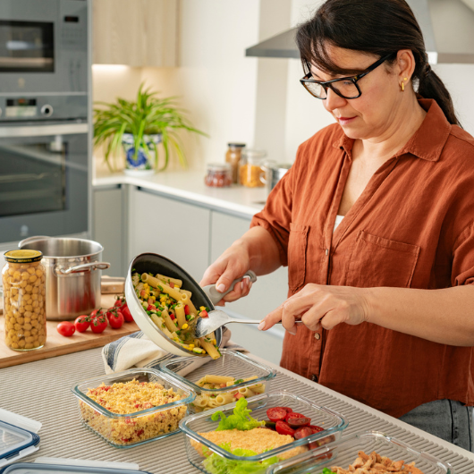 Woman in the kitchen preparing healthy homemade weekly meals in glass containers.