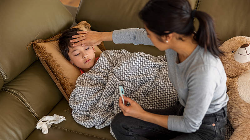 mother measuring the temperature of her son at home