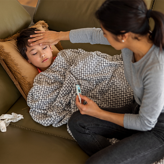 mother measuring the temperature of her son at home