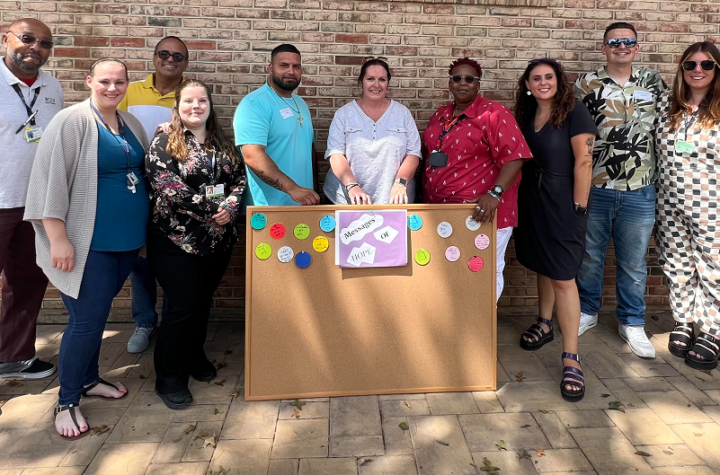 The team at Black Recovery Center standing and smiling for a fundraiser that provides life-changing books for patients recovering from addiction.