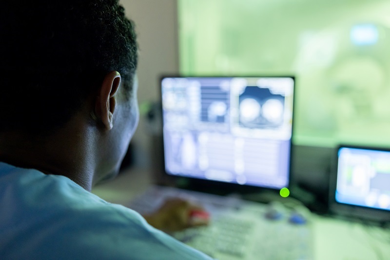 An over-the-shoulder view of a physician reviewing scans.