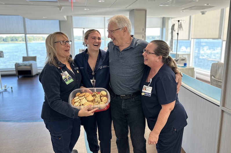 Albert standing with nurses in the infusion center, smiling and hugging each other. 