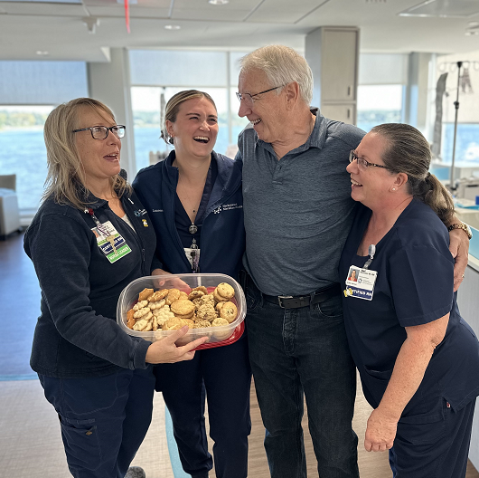 Albert standing with nurses in the infusion center, smiling and hugging each other. 