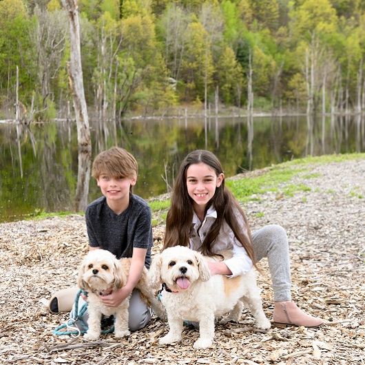 Children, Aiden and Lia, hanging out with their dogs in the park by a pond