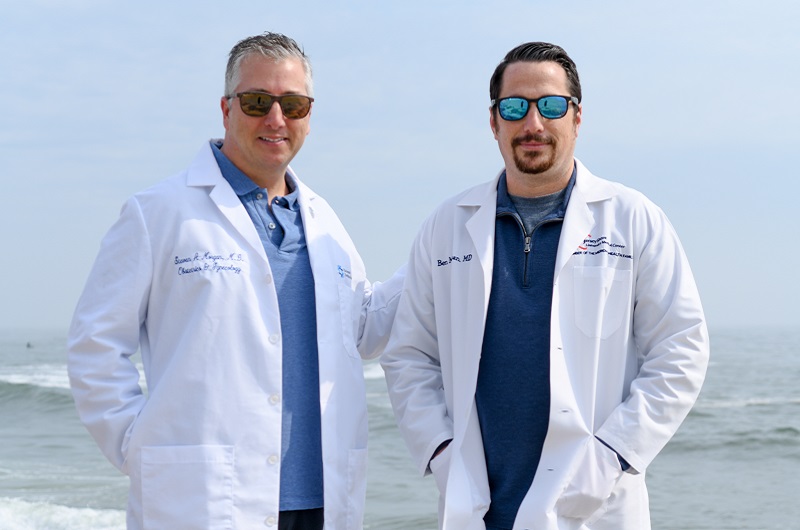 Brothers Steven Morgan, M.D., and Benjamin Morgan, M.D. standing on the boardwalk in front of the ocean.