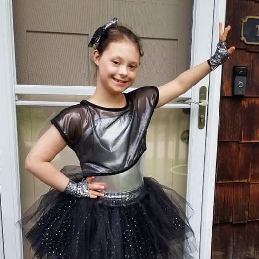 Ally Kistler standing outside her house, in a dance pose for a dance recital 