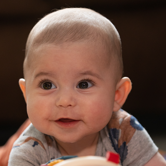 Baby Benny doing some tummy time, with his toys, smiling.