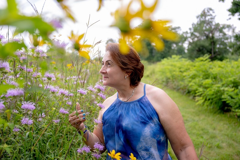 Adriana smelling flowers outside in a field.