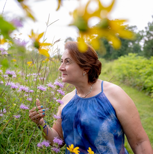 Adriana smelling flowers outside in a field.