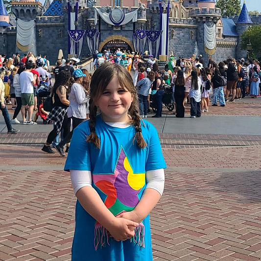 6-year-old Gitty Rubin standing smiling while at a Disney park.