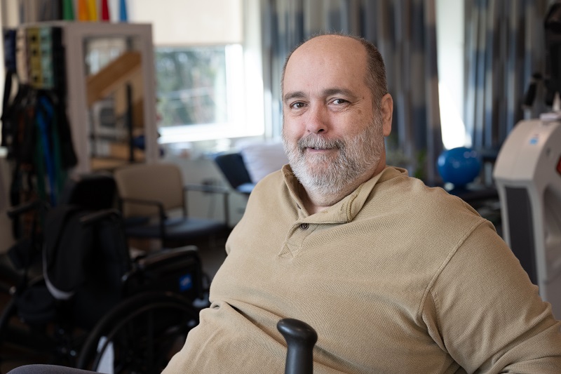 George Verblaauw smiling, while sitting on a stationary bike, working on rehabilitation.