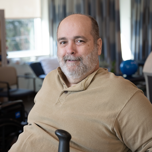 George Verblaauw smiling, while sitting on a stationary bike, working on rehabilitation.
