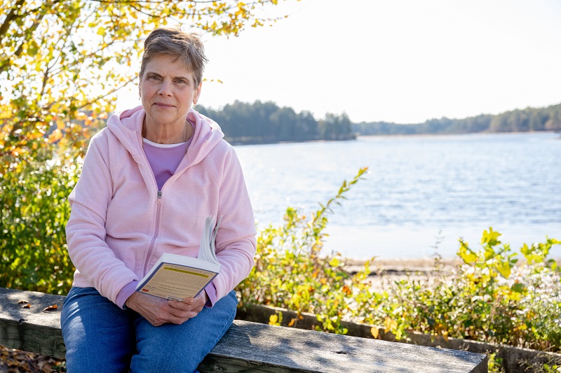Gail DiPaolo sitting outside by a body of water.